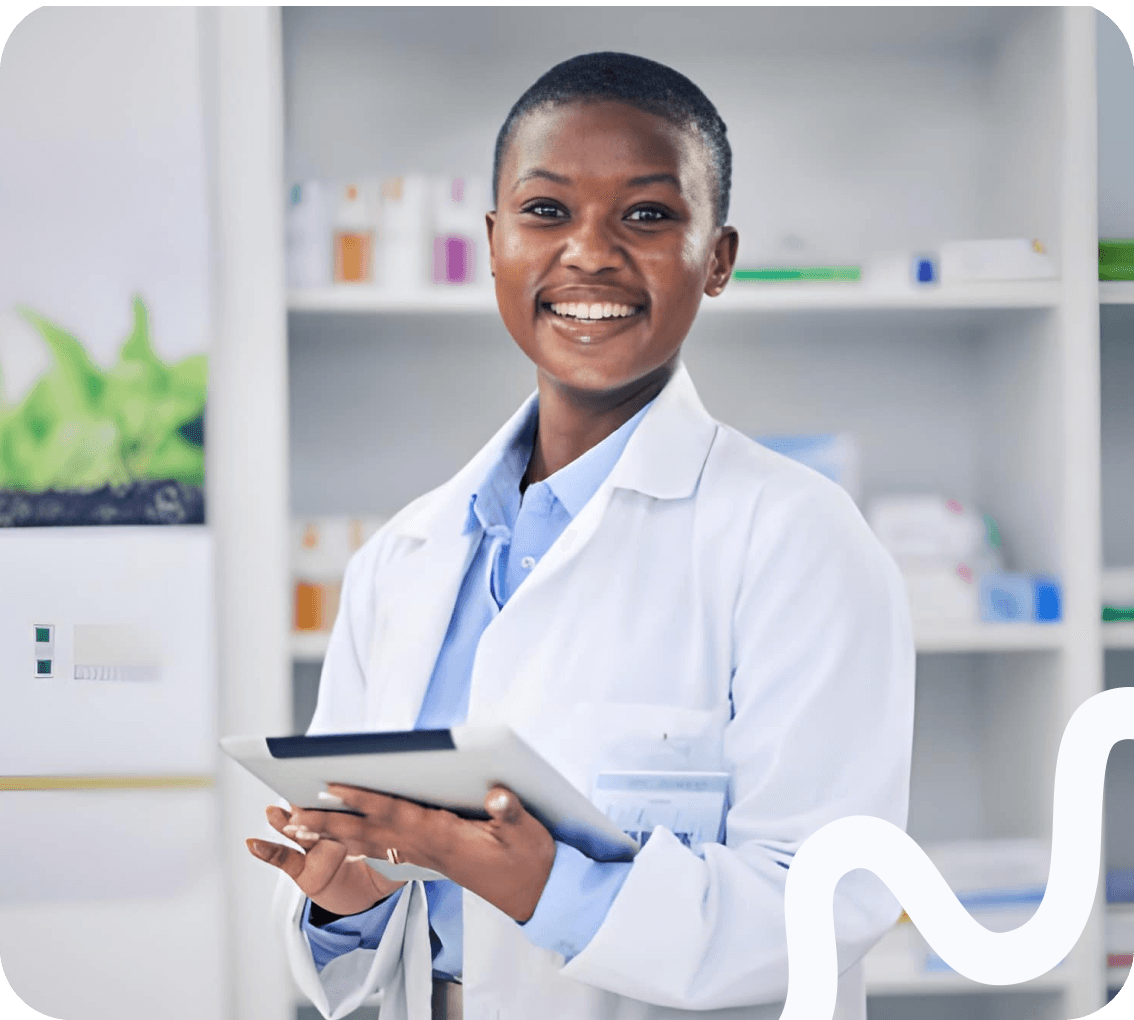 A pharmacist holding a tablet in front of stocked shelves