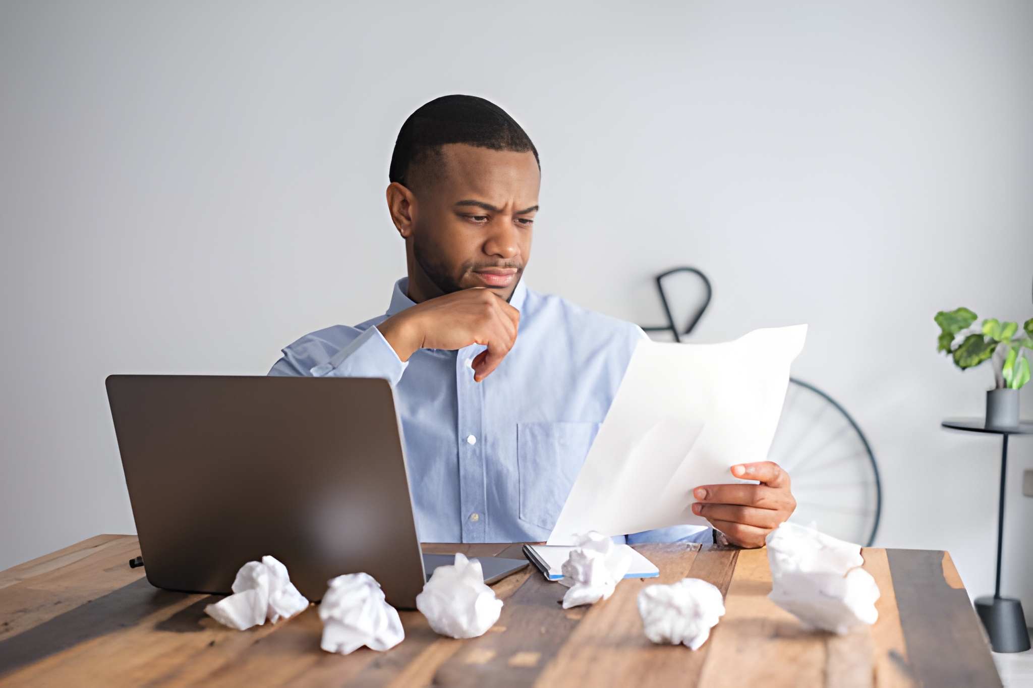 A business owner frowning at paperwork surrounded by crumpled pages